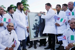 Các bác sĩ Cuba cầm di ảnh cố Chủ tịch Fidel Castro trong buổi lễ chia tay đoàn hỗ trợ y tế sang Italy giữa đại dịch Covid-19 tại Havana hồi tháng 3/2020. Ảnh: Reuters
